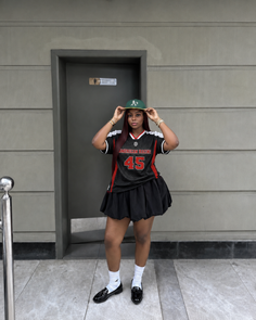 Woman in a baseball jersey and mini skirt posing outdoors
