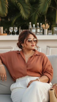 Woman in sunglasses and a brown shirt sitting outdoors