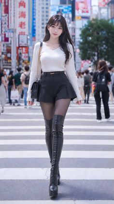 Woman with long dark hair in a white sweater and black shorts on a city street