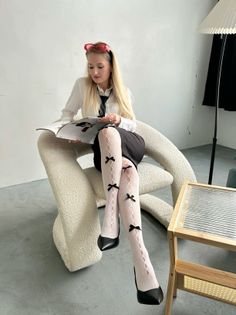 Woman with long blonde hair in a white shirt and black tie reading a magazine