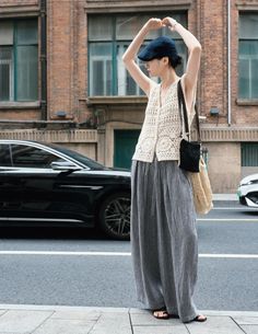 Woman in a crochet vest and wide leg pants on a city street