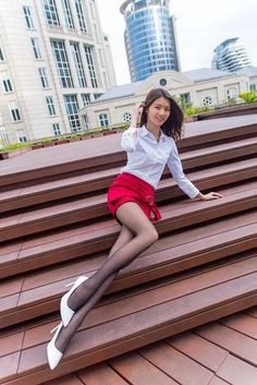 Woman in a red skirt and white shirt posing on wooden steps outdoors