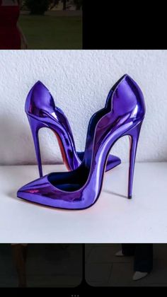 Pair of shiny purple stiletto heels with red soles on a white surface