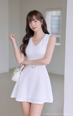 Woman in a white dress with a quilted bag posing indoors
