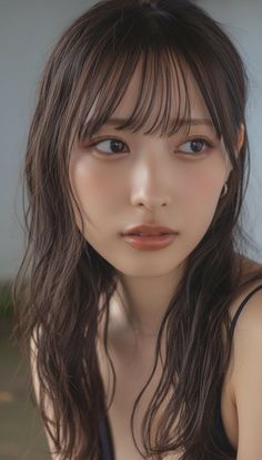 Woman with long, wet dark hair and natural makeup in a soft-lit portrait