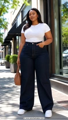 Woman in a white t-shirt and dark wash jeans standing on a street