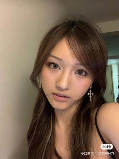 Woman with long brown hair and cross earrings in an indoor portrait