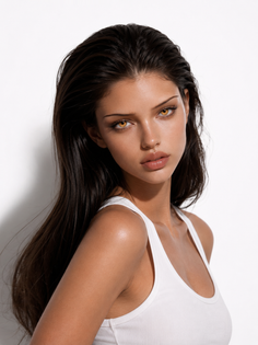 Woman with long dark hair and amber eyes wearing a white tank top