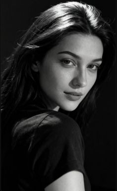 Woman with long dark hair looking over her shoulder in a black and white portrait
