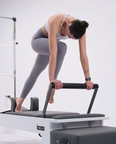 Woman in athletic wear performing an exercise on a pilates reformer