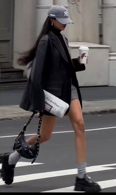 Woman in a black blazer and mini skirt walking across a crosswalk