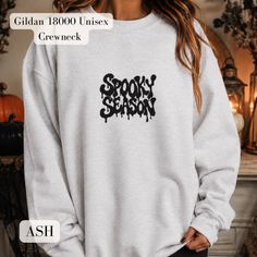 Woman wearing a grey crewneck sweatshirt with "Spooky Season" text