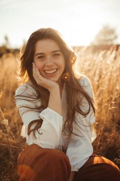 Smiling woman with long hair in a white shirt, bathed in golden hour sunlight