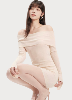 Woman in an off-shoulder dress and high heels squatting in a studio