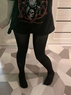 Person wearing black tights and an oversized t-shirt with a skull graphic