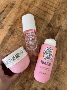 Three pink body care products on a wooden surface