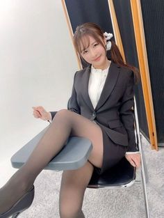 Woman in a business suit and black pantyhose sitting indoors