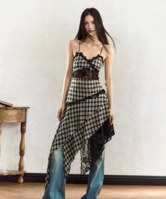 Woman with long hair wearing a plaid dress with lace trim over jeans indoors