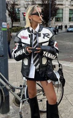 Woman in a motorcycle jacket, mini skirt, and knee-high boots on a city street