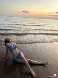 Woman in a blue bikini lying on a beach at sunset