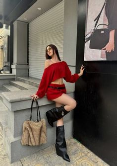 Woman in a red crop top and mini skirt with black boots and a furry bag