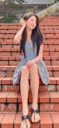 Woman in a striped dress sitting on brick stairs outdoors