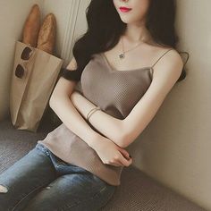Woman in a ribbed top and jeans with a bag of baguettes and sunglasses