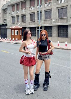 Two women posing on a street in front of a building