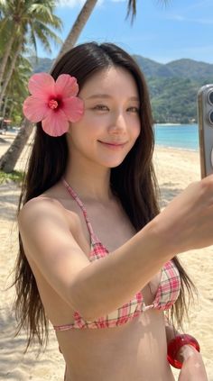 Woman in a pink plaid bikini taking a selfie on a sunny beach
