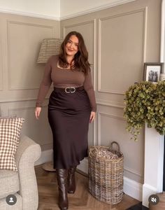 Woman in a brown top and skirt with boots posing indoors