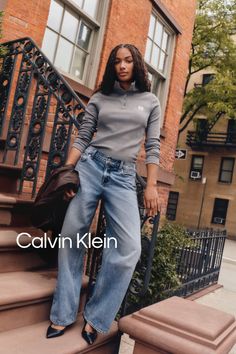 Woman in a grey long sleeve shirt and wide leg jeans on a city street