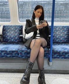 Woman in a black blazer and mini skirt sitting on a subway train