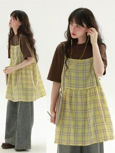 Woman in a plaid dress and wide leg jeans with earbuds on a white background
