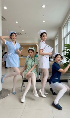 Four women in nurse uniforms and white stockings posing in a hospital setting