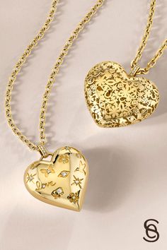 Two gold heart pendants with intricate designs and diamond accents