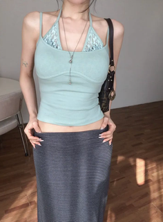 Woman in a light blue halter top and striped skirt, showing midriff
