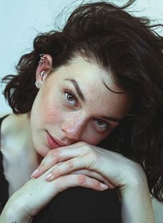 Woman with dark hair and freckles looking at the camera