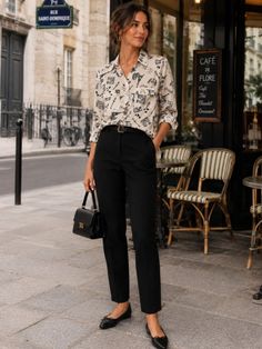 Woman in a printed shirt and black pants standing outside a cafe