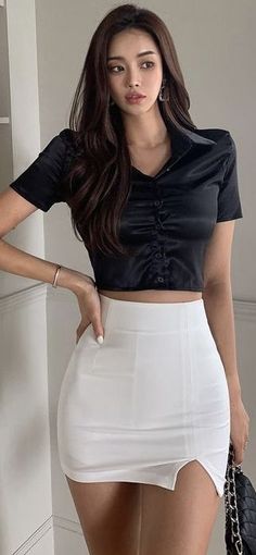 Woman with long hair wearing a black crop top and white mini skirt indoors