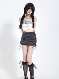Woman with long braids wearing a crop top and denim skirt with knee-high socks