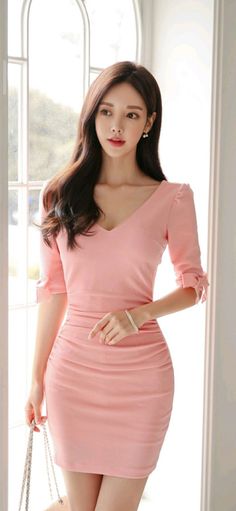Woman in a pink ruched dress with long dark hair indoors