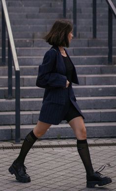 Woman with short hair wearing a pinstripe suit and chunky shoes outdoors