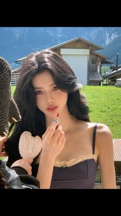 Woman with long black hair wearing a spaghetti strap top with lace trim outdoors