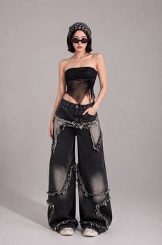 Woman in a sheer top, distressed jeans, bandana, and sunglasses posing in a studio