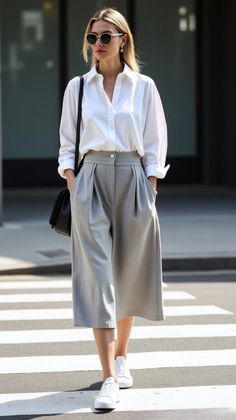 Woman in a white shirt and grey culottes walking on a crosswalk