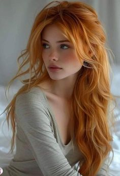 Woman with long red hair and blue eyes in a grey shirt