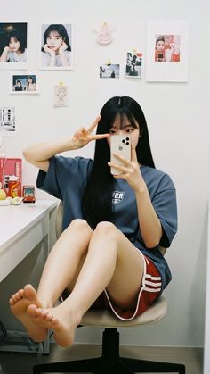 Woman with long black hair taking a mirror selfie in a t-shirt and shorts