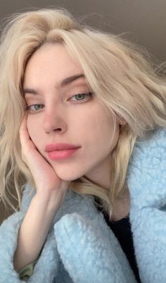 Woman with blonde hair and blue eyes wearing a blue coat