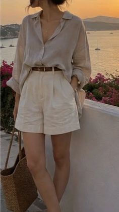 Person in a linen shirt and shorts with a straw bag at sunset