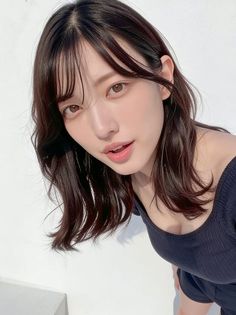 Woman with dark hair and an off-shoulder top looking at the camera